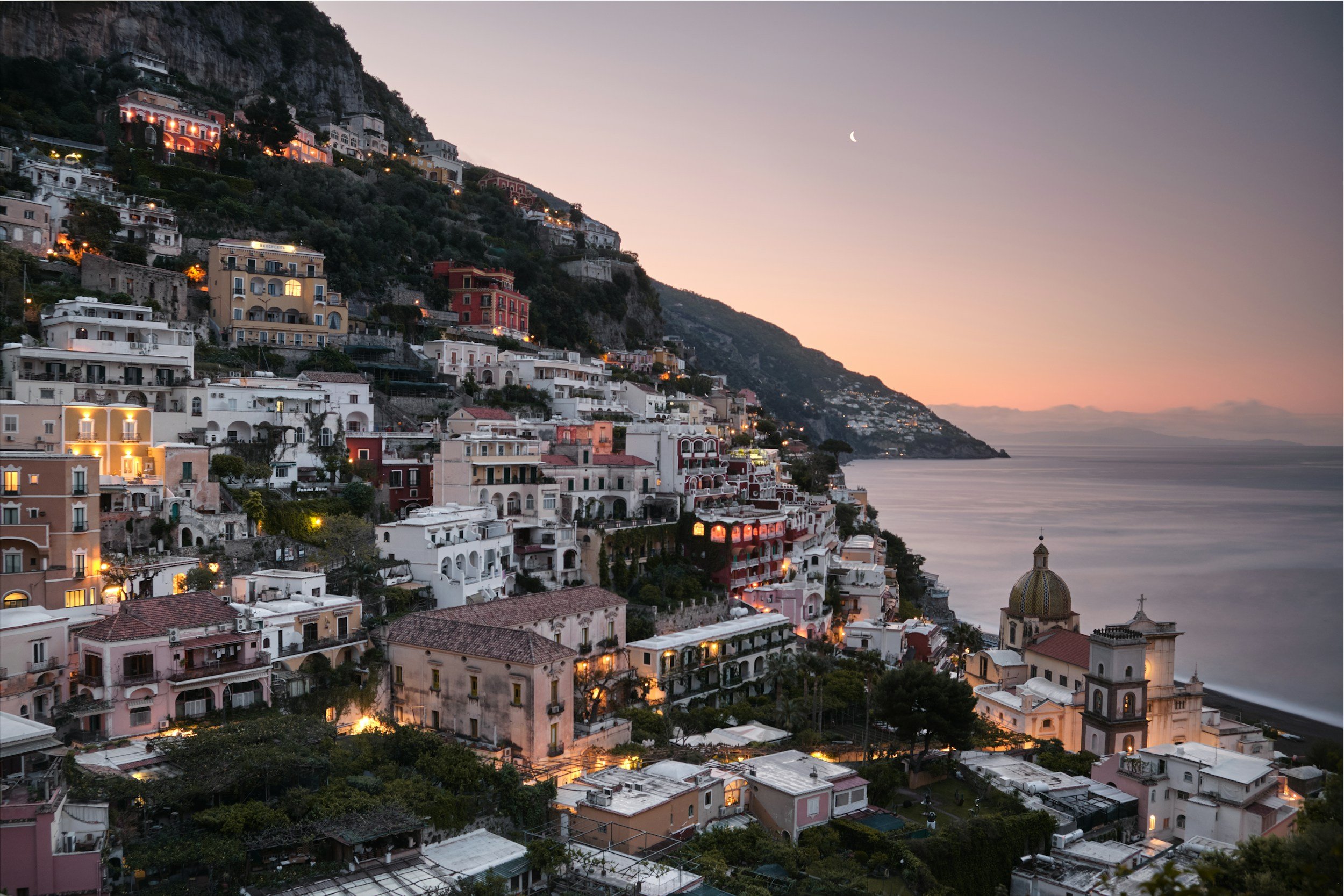 Positano's lights coming on at dusk below the cliffs