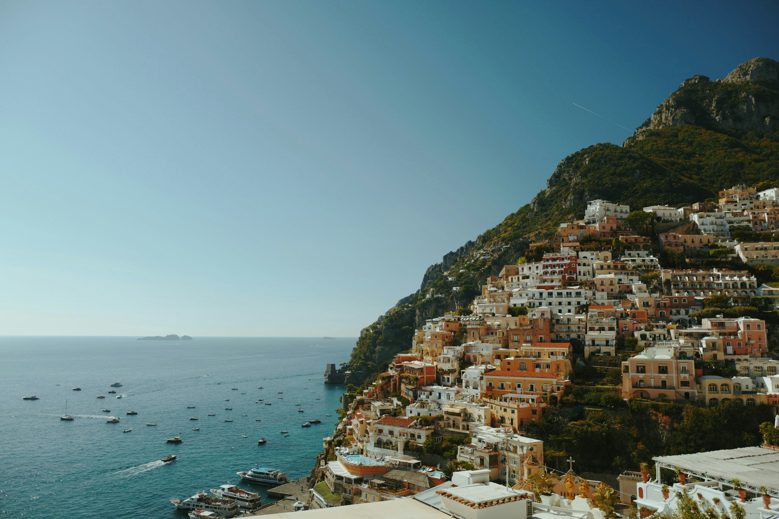 Positano's houses stacked up the hillside above boats moored in the bay