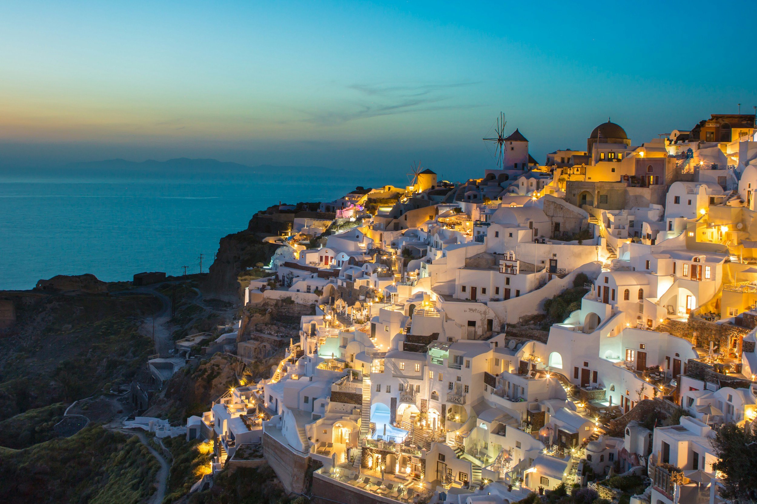 Oia on Santorini lit up at dusk above the caldera