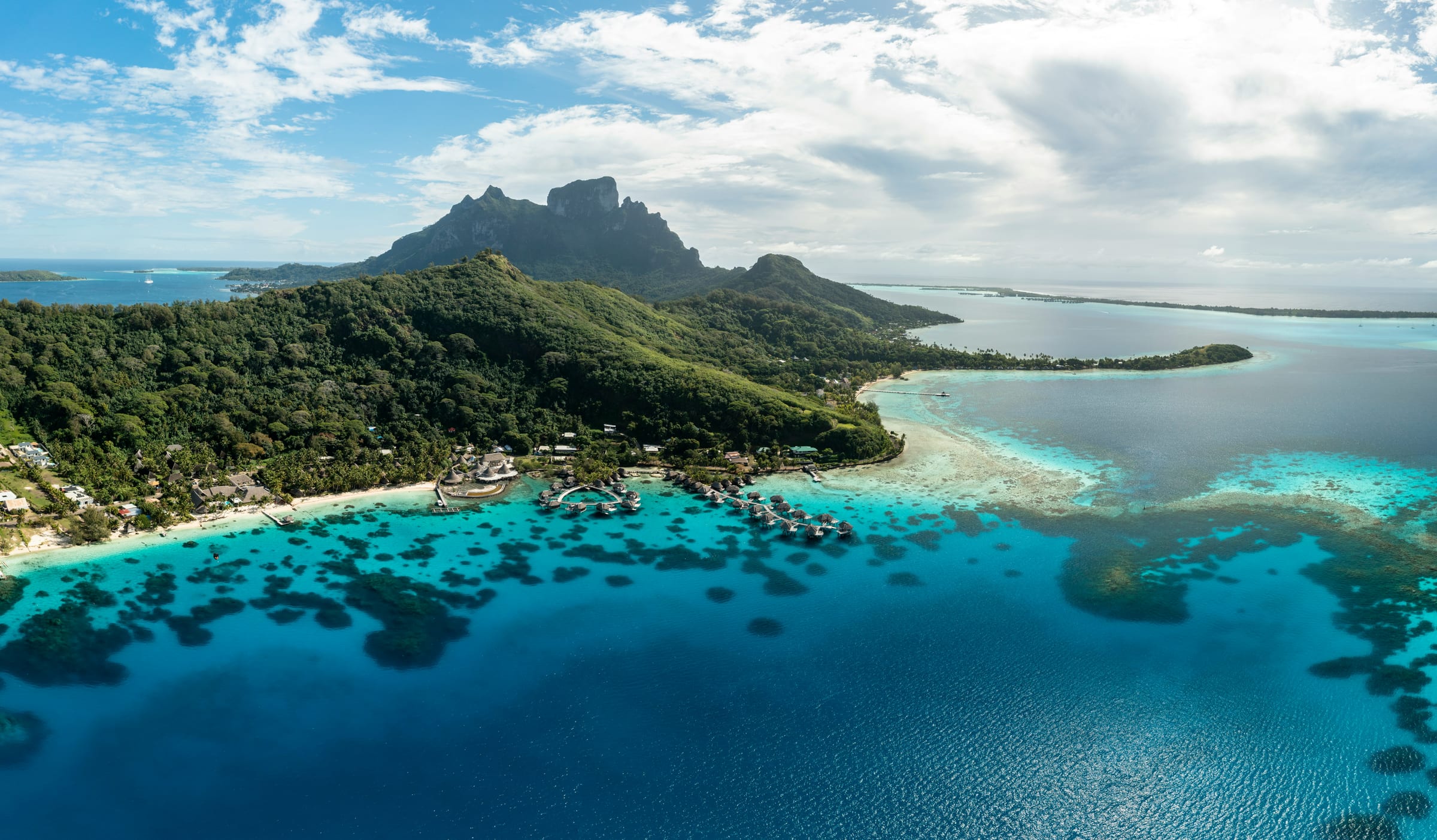 Overwater bungalows over a turquoise lagoon with Mount Otemanu behind in Bora Bora