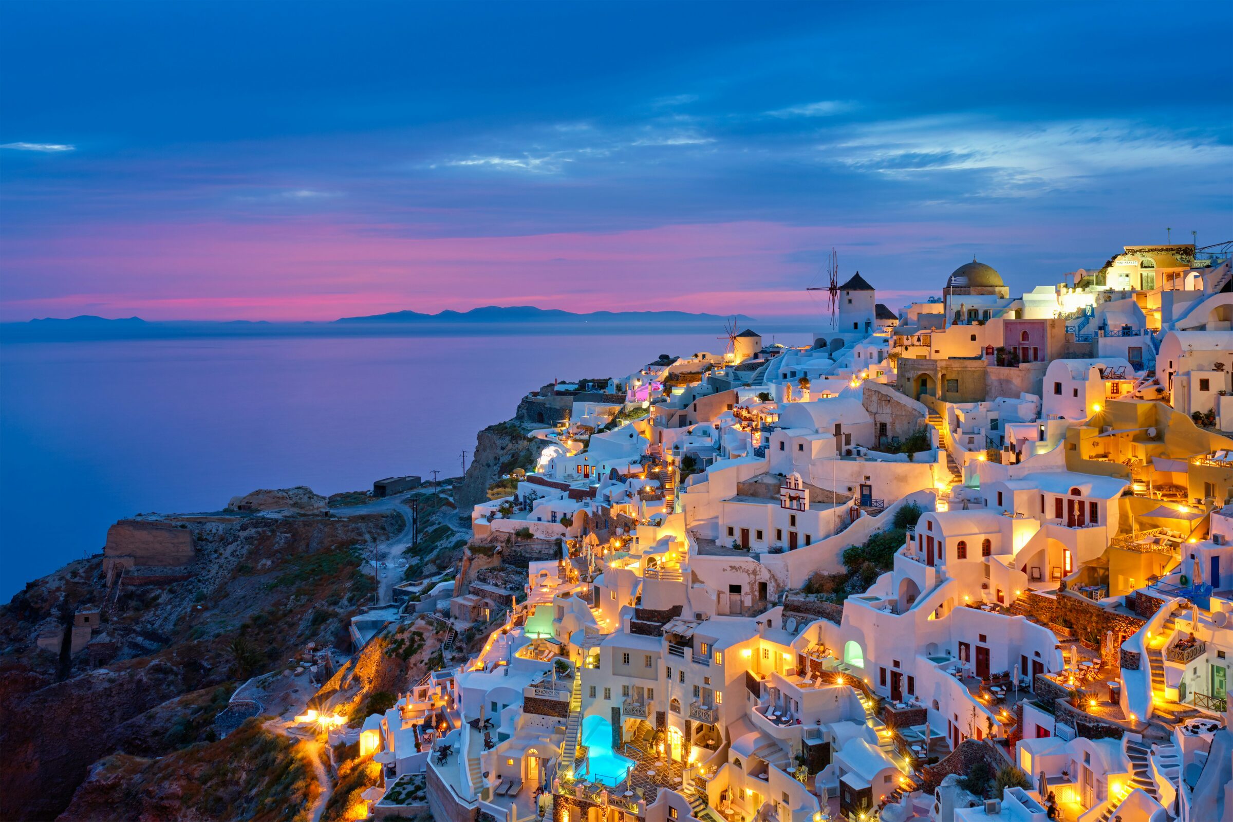 Whitewashed cliffside houses and blue domes above the caldera in Santorini, Greece