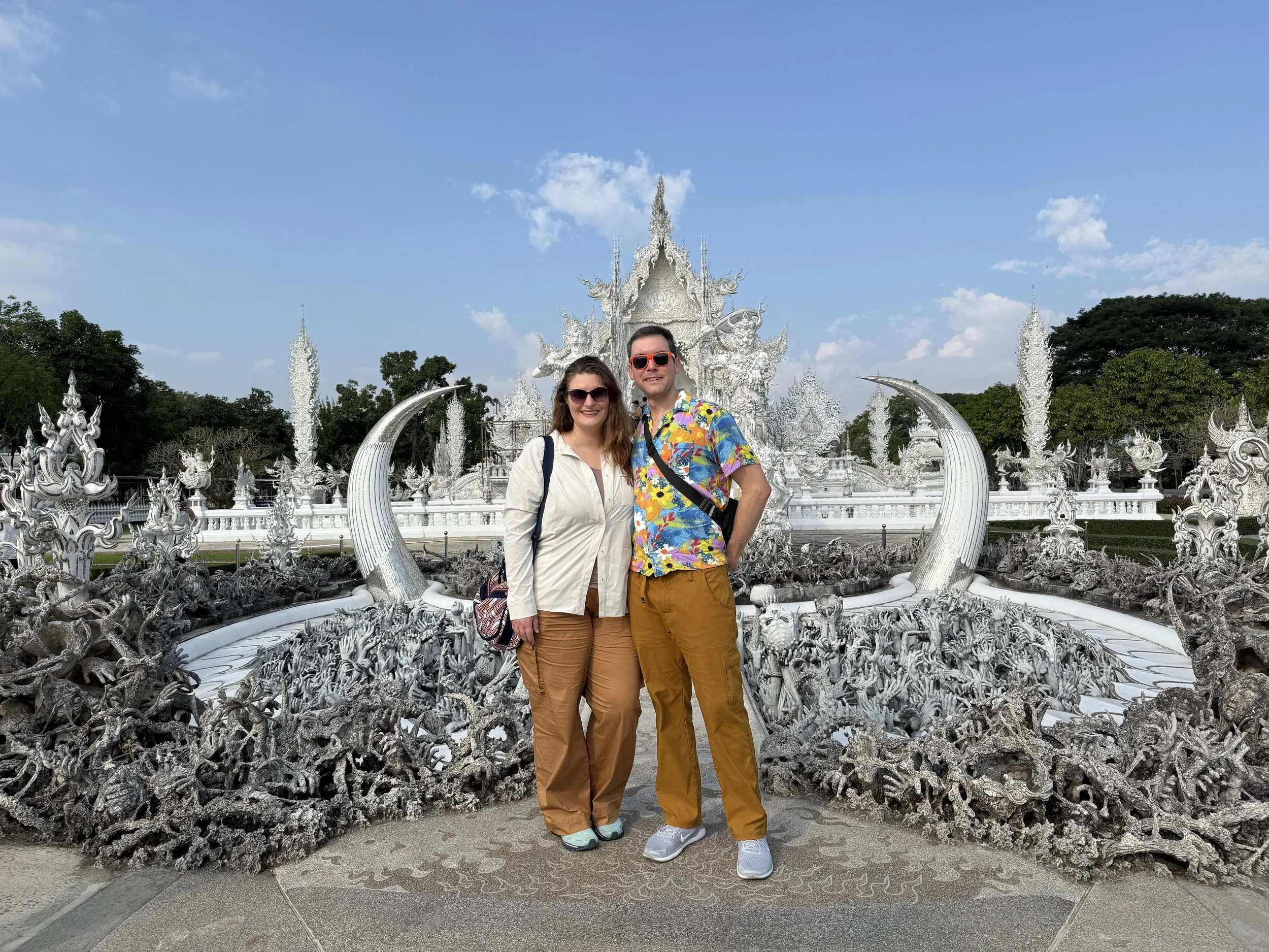 Erinn and Matt in front of the white ornate Wat Rong Khun temple in Chiang Rai, Thailand.