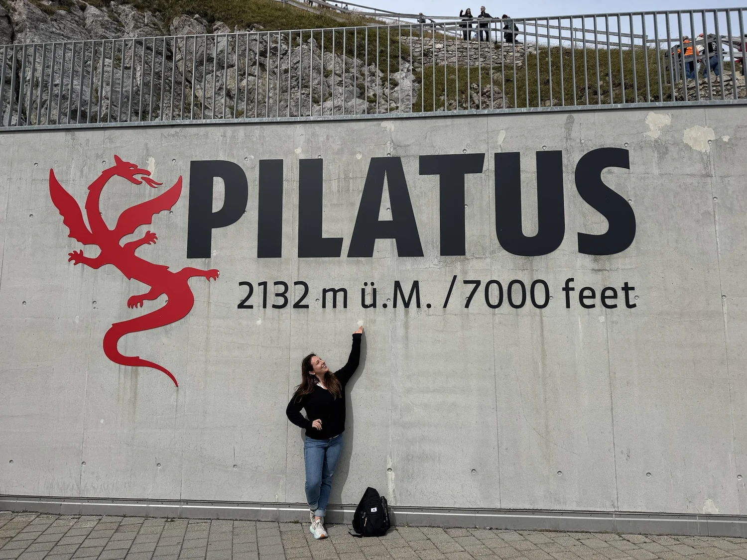 Rachel reaching up to the Mt. Pilatus altitude sign in Switzerland during her solo Europe trip.